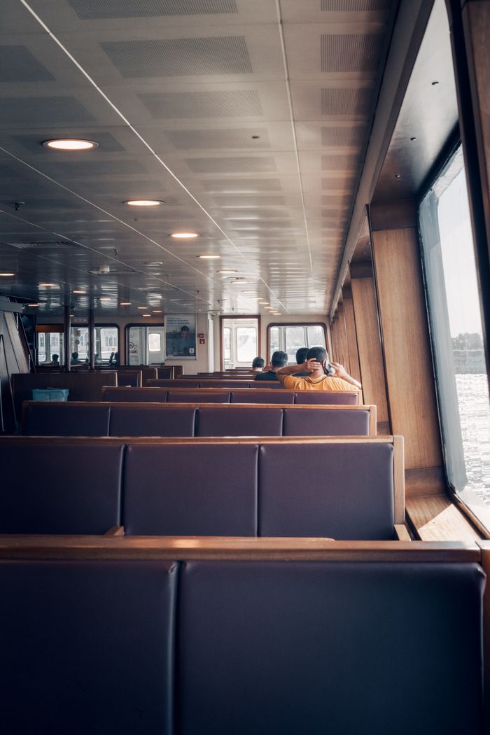 collection-04 Interior view of a passenger ferry showcasing empty seats and windows with a view of the water.