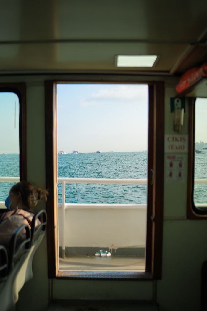 collection-03 A glimpse of the sea through a ferry window with a passenger relaxing inside.