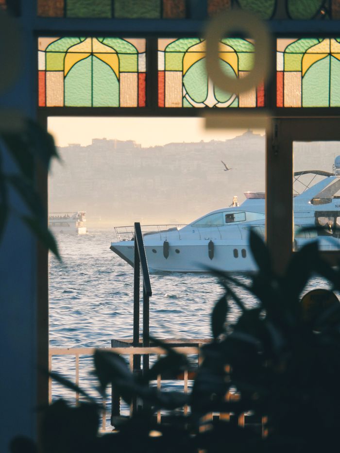 about-us-02 Serene view of luxury yachts seen through a stained glass window over a calm sea at day.