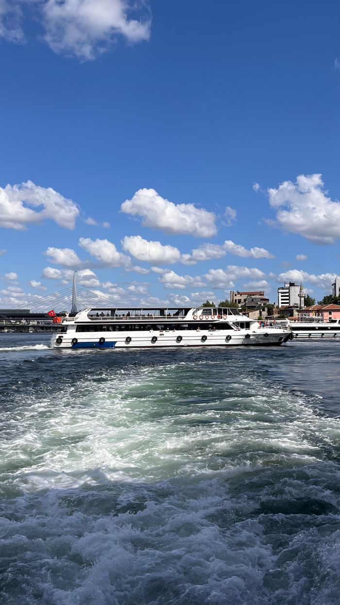 faq-img A luxurious yacht glides on a sunny day with a vibrant skyline and serene water.